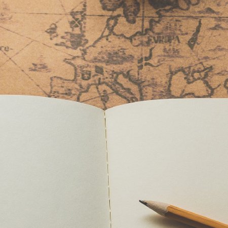 Open journal and pencil on a map